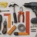 Assorted DIY home repair tools including hammer, screwdriver, wrench, and drill on a workbench