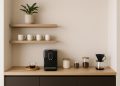 Modern minimalist coffee nook with compact espresso machine, open shelving, and stylish mugs